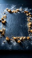 Overhead view of brown sugar crystals and powdered sugar scattered on dark slate surface, creating a culinary frame for food photography and recipe styling.