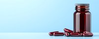 Brown glass medicine bottle with scattered red gel capsules on reflective surface against light blue background, minimalist pharmaceutical composition.