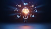 Glowing light bulb with brain inside surrounded by business icons on dark blue background representing innovation and creative thinking in commerce.