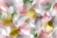 Soft pastel circles in pink, gold, mint green and white create dreamy bokeh effect background pattern with overlapping transparent shapes.