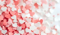 Pink and white heart-shaped confetti scattered in soft focus creating romantic pattern background, suitable for Valentine's Day designs and love-themed projects.