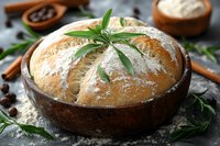 Fresh baked round artisan sourdough bread in wooden bowl, dusted with flour and decorated with rosemary sprigs, rustic food photography setup.