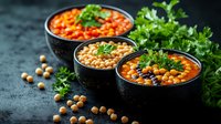 Spicy chickpea soup garnished with fresh parsley in black bowls. Traditional Mediterranean cuisine with legumes and vegetables on dark background.