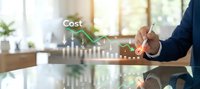 Businessman analyzing cost reduction data on digital interface with declining arrow graphs and financial charts in modern office environment.