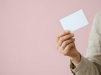 Hand holding blank white card against pink background, suitable for business card mockups, branding presentations, and marketing materials.