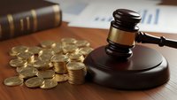 Wooden gavel with golden coins and legal documents on desk representing financial law, bankruptcy proceedings, and monetary legal disputes in courtroom.