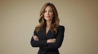 Professional businesswoman in black suit with crossed arms standing confidently against neutral background for corporate presentations.