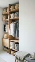 Modern wooden wardrobe organization system with natural wicker baskets, hanging clothes, and minimalist bedroom storage solutions for home interior design.