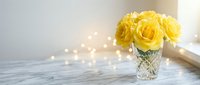 Yellow roses in crystal vase on marble surface with warm bokeh lights creating elegant home decor atmosphere for romantic occasions and interior design.