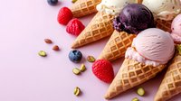 Fresh ice cream scoops in waffle cones with berries and pistachios on pink background. Sweet summer dessert composition for menu or packaging design.