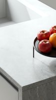 Minimalist kitchen counter with red and golden apples in black bowl on white marble surface, modern interior design and home decor styling.