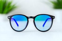 Modern round black frame sunglasses with blue gradient lenses on white background, stylish eyewear accessory for fashion and optical design projects.
