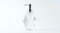 Modern clear glass soap dispenser with chrome pump on white background isolated for bathroom decor and hygiene products design.