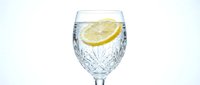 Refreshing glass of sparkling water with fresh lemon slice and ice cubes, isolated on white background for beverage, wellness and hydration design projects.