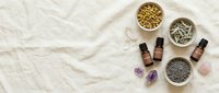 Natural wellness spa setup with essential oil bottles, healing crystals, and organic seeds on neutral linen background for aromatherapy and holistic health.
