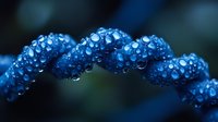 Twisted blue spiral covered in water droplets against dark background creates mesmerizing macro photography effect with bokeh and reflective surfaces.