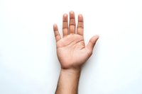 Open palm of light-skinned male hand raised against white background, showing lines and details of palm, suitable for fortune telling or palm reading concepts.