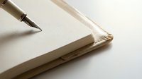 Fountain pen nib resting on blank cream notebook page, suitable for writing, journaling, stationery design, and creative projects.