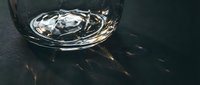 Glass of water with ice cubes on dark textured surface, suitable for beverage, refreshment, and lifestyle design projects.