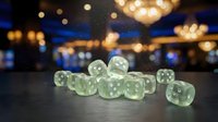 Translucent green dice with white dots arranged on dark surface against blurred golden and blue bokeh lights, suitable for gaming, gambling, entertainment, and chance-related content.