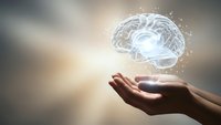 Human hands holding glowing brain hologram with neural connections representing artificial intelligence, mental health, neuroscience and cognitive technology concepts.