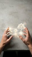 Hands holding glowing lotus flower and tree with magical light particles and rainbow prism effect against concrete background for spirituality and wellness design.