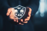 Businessman holding glowing shield with home, car, and plane icons, symbolizing comprehensive insurance and asset protection concept.