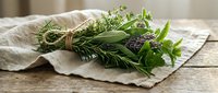 Fresh herb bundle with rosemary, sage and lavender tied with twine on linen cloth, rustic kitchen styling for culinary and aromatherapy applications.