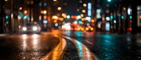 Blurred city street at night with colorful bokeh lights reflecting on wet asphalt pavement creating atmospheric urban scene for backgrounds and mood concepts.