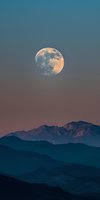Full moon rising above layered mountain silhouettes at dusk, with warm golden lunar light illuminating the night sky for astronomy and nature backgrounds.