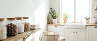 Organized kitchen counter with glass storage containers, dried goods, potted plants, and natural light from windows, suitable for home decor and lifestyle content.