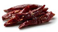 Dried red chili peppers with visible seeds on white background, macro shot showing texture and spicy details, food ingredient for cooking and seasoning.