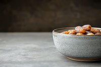 Fresh roasted almonds in rustic ceramic bowl on concrete surface against dark background, minimalist food styling for healthy snacking and cooking.