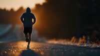 Silhouette of male runner jogging on rural road during golden hour sunset. Athletic man exercising outdoors with warm sunlight creating dramatic backlit scene.