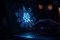 Glowing blue snowflake hologram floating above laptop keyboard in dark room with bokeh lights creates magical winter atmosphere for technology concept.