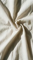Crumpled natural linen fabric with soft folds and shadows, showcasing texture and drape for textile, interior design, and fashion projects.