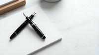 Elegant black fountain pen and ballpoint pen set on white marble surface for professional writing and business correspondence.