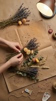 Florist arranging dried lavender and yellow flowers with eucalyptus on kraft paper, overhead view with hands holding bouquet for floral design, craft, and wedding planning projects.