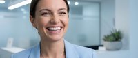 Professional businesswoman smiling confidently in modern office environment with natural lighting and contemporary workspace background.