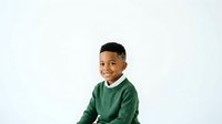 Smiling young boy with dark skin tone wearing green sweater, isolated on white background for portrait and commercial use.