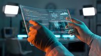 Hands in gloves holding transparent digital tablet with holographic data interface and code visualization in modern tech laboratory environment.