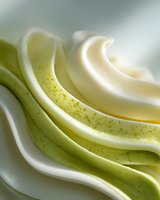 Creamy swirls of soft serve ice cream in vanilla and matcha green tea flavors with delicate matcha powder sprinkled on top, perfect for dessert menus.