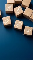 Wooden blocks with healthcare icons including syringe, bandage, heart and leaf symbols on blue background for medical wellness concept design.