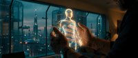 Young male professional with medium brown skin tone holding glowing digital human figure hologram against cityscape window at night, representing technology innovation and future business solutions.