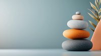 Zen stones balanced in modern minimal composition with orange and gray pebbles against soft blue background, decorative elements create peaceful atmosphere.