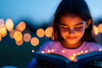 Young Asian girl reading magical glowing book at dusk with bokeh lights creating dreamy atmosphere. Soft illumination highlights child's enchanted expression.