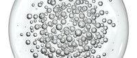 Macro shot of transparent spheres or bubbles suspended in clear liquid, creating an abstract pattern of floating particles with reflective surfaces and depth of field effect.