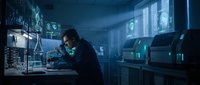 Male scientist working late night in modern laboratory with glowing equipment and computer screens analyzing data for research breakthrough.
