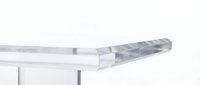 Clear transparent corner guard protector on white table edge for child safety and furniture protection against impacts and bumps in home environment.