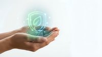 Hand holding glowing green leaf shield icon with neon light effect, representing environmental protection, sustainability, and eco-friendly security for web and digital design.